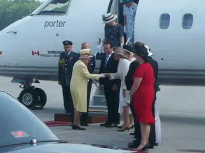Queen Elizabeth shaking hands with people after departing a plane at YKF