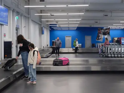 Passenger picking up luggage in YKF arrivals building