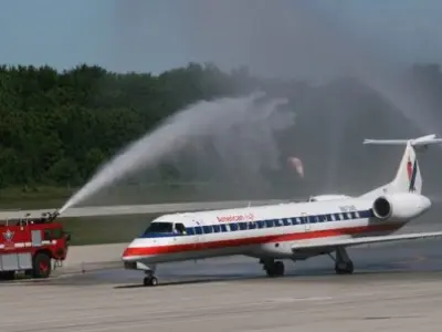 American Airlines airplane at YKF with a fire truck spraying water over the plane on the runway